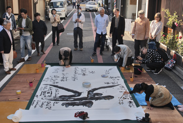 昨2018年の鬼才書家和田克己氏による姉小路路面での実演と書道指導のようす