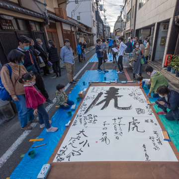 昨2021年の鬼才書家和田克己氏の書を囲んで。姉小路路面での書道のようす